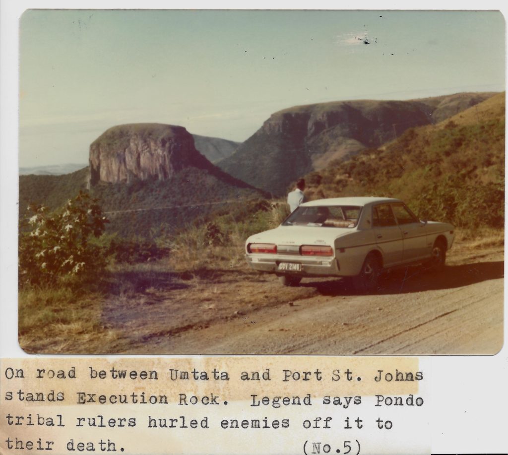 A car parked on the side of a road near mountains.