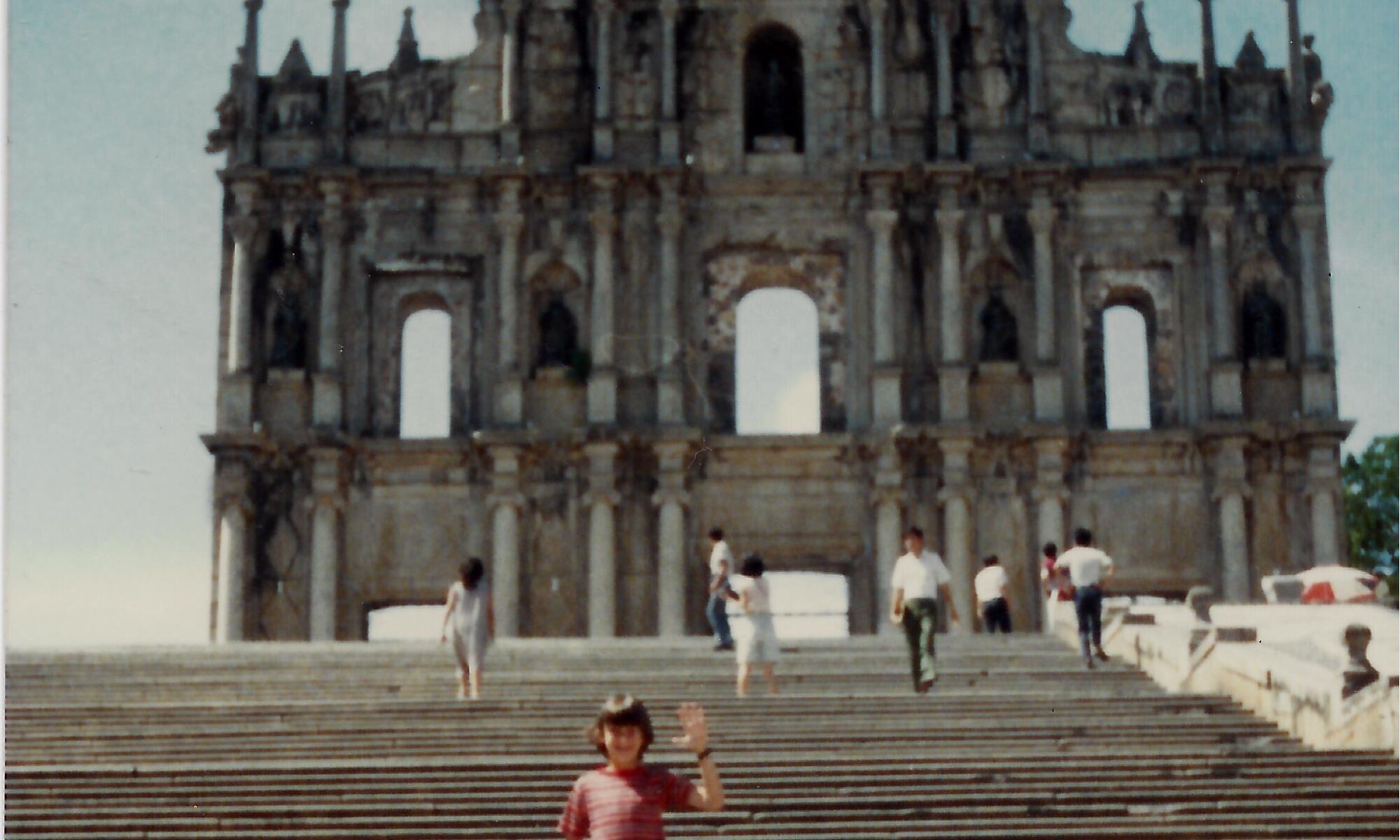 Child standing before historic stone building.