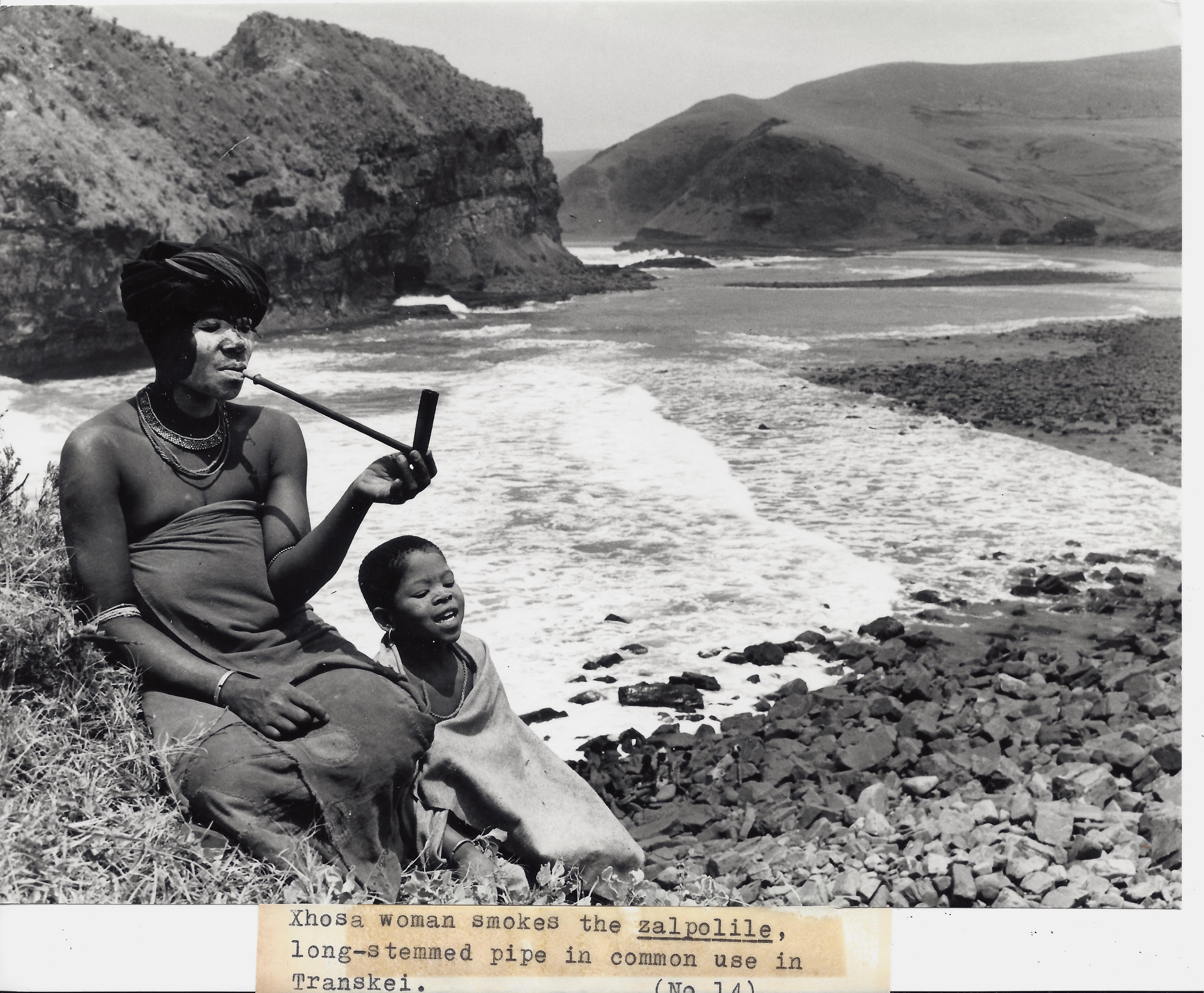 A woman and child sitting on the beach.