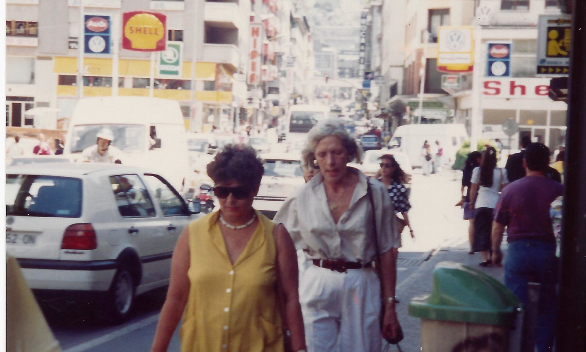Two women walking down a street with shopping bags.