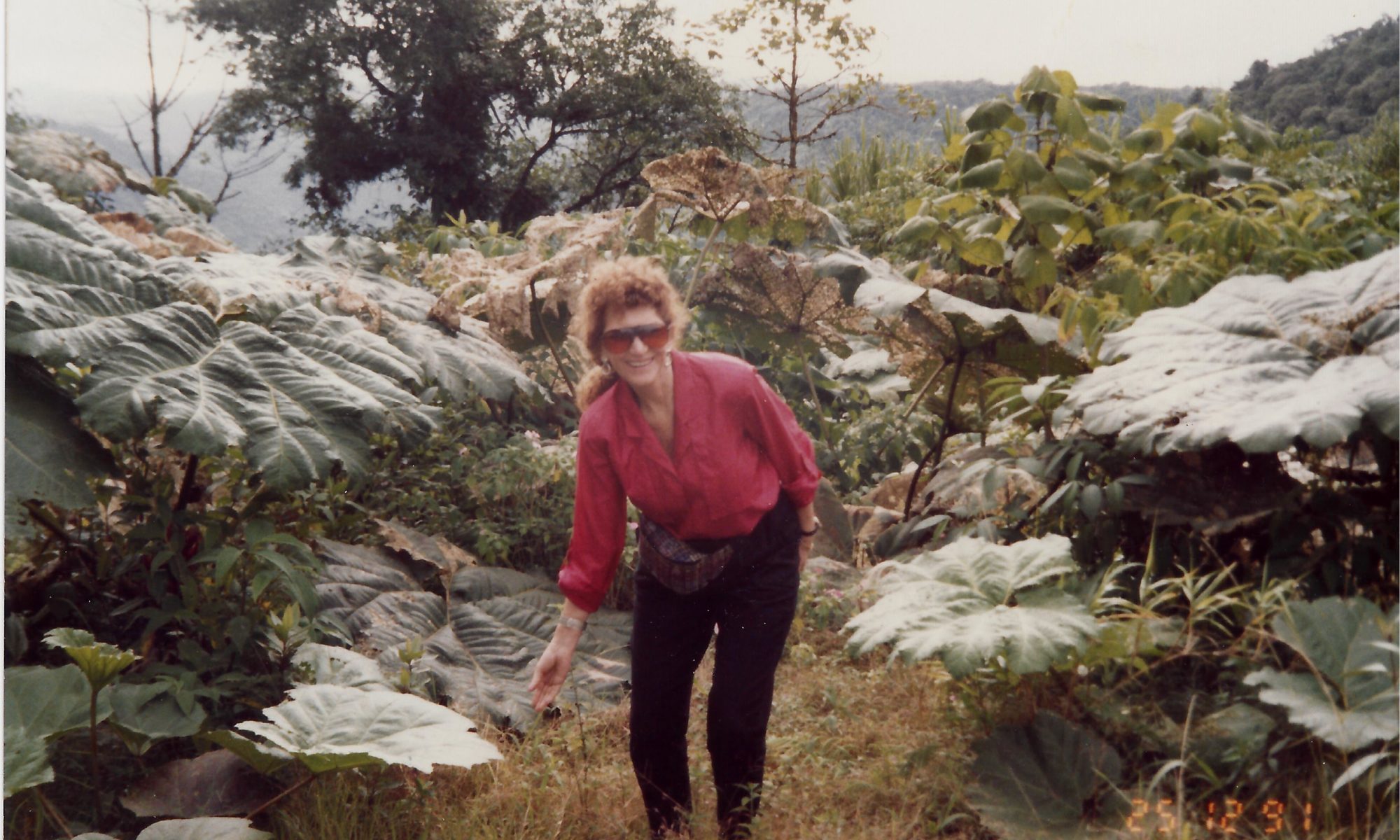 A woman in red shirt and black pants standing on grass.
